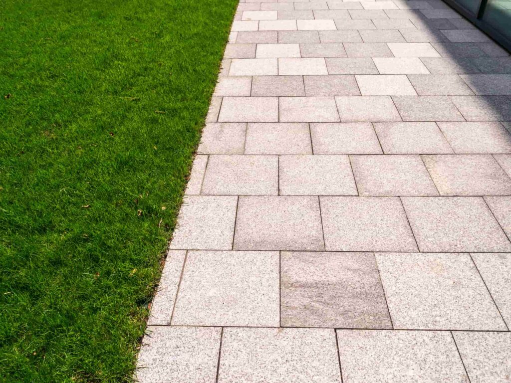 This is a newly installed patio area in grey slabs, with turf grass next to it