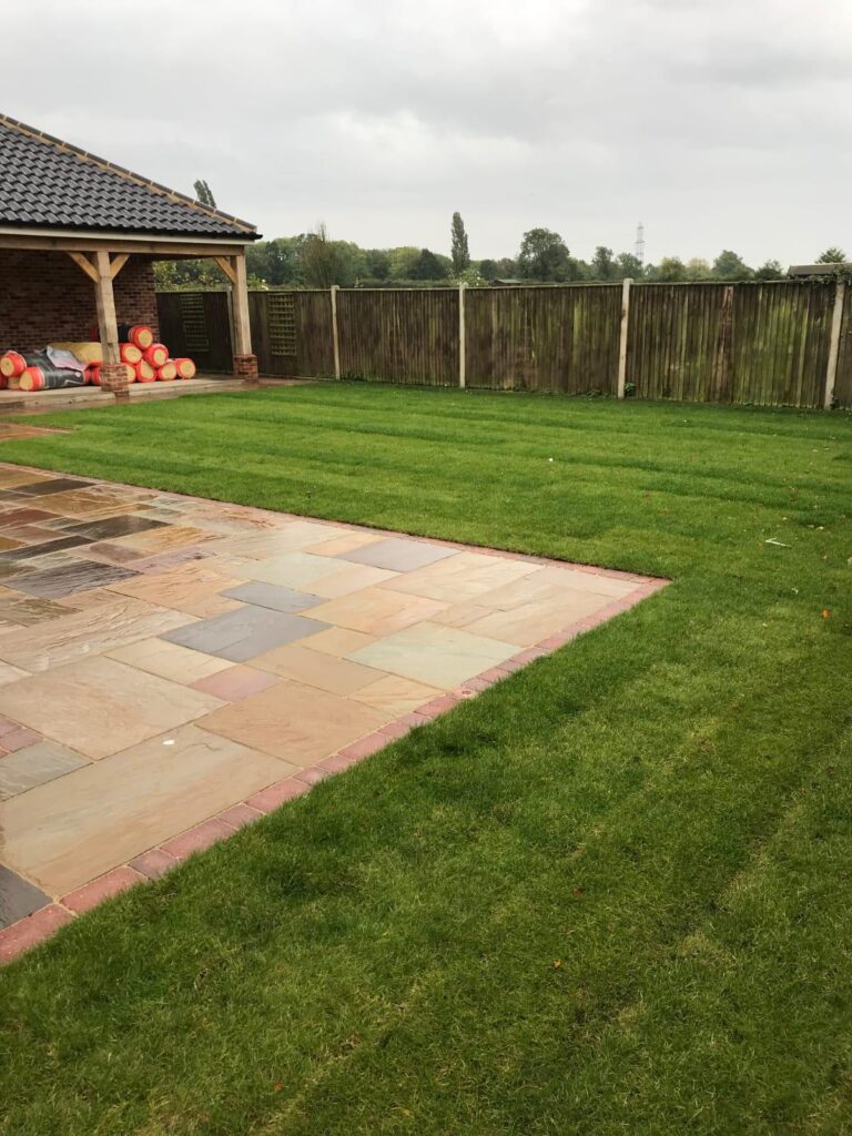 This is a newly installed patio area in grey slabs, with turf grass next to it